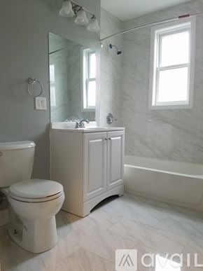 Boston apartment for rent - A white bathroom with a toilet, sink, and bathtub.