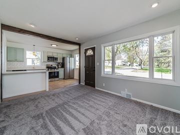 Saint Paul house for rent - A spacious living room with a kitchen in the background and a grey carpet on the floor.