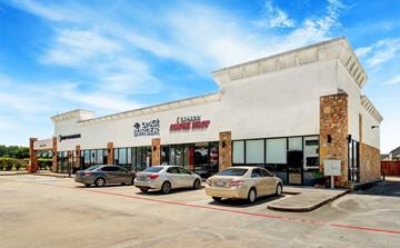 Spring apartment for rent - A car dealership with a white building and two cars parked in front.