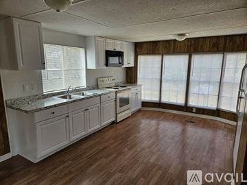 Spring Hill house for rent - A kitchen with white cabinets and a granite countertop.