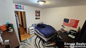 Boston house for rent - A bedroom with a bed, desk, and American flag on the wall.