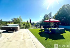 Los Angeles house for rent - A sunny day in a backyard with a hot tub and a red umbrella.