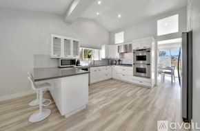 Los Angeles house for rent - A modern kitchen with white cabinets and a wooden floor.