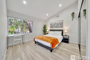 Los Angeles house for rent - A bedroom with a large bed and a view of trees outside the window.