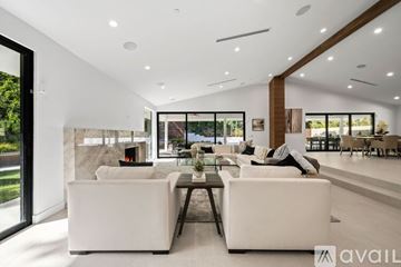 Los Angeles house for rent - A modern living room with white furniture and a fireplace.
