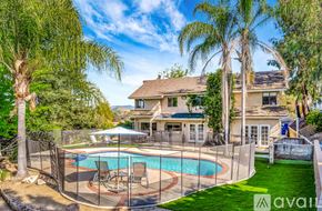 Agoura Hills house for rent - A house with a pool surrounded by a fence and trees.