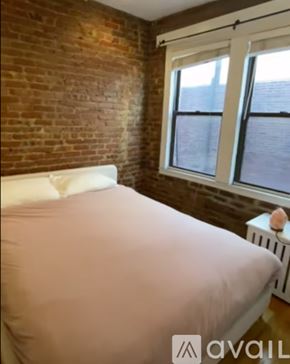 Boston apartment for rent - A bedroom with a white bedspread and a brick wall.