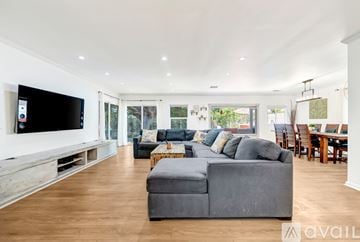Los Angeles house for rent - A spacious living room with a grey sofa and a television on the wall.