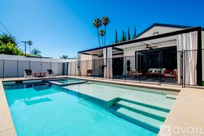 Los Angeles house for rent - A pool with a glass barrier and a white building in the background.