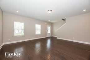 Hermitage house for rent - A spacious room with wooden floors and a staircase in the background.