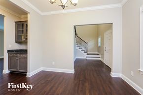 Clemmons house for rent - A spacious room with wooden floors and a staircase leading to another room.