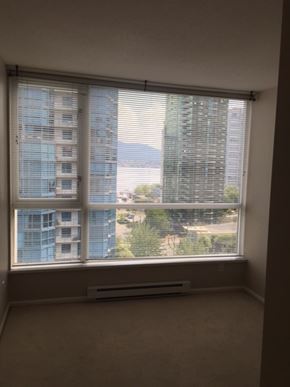 Vancouver apartment for rent - A window with blinds overlooking a cityscape.