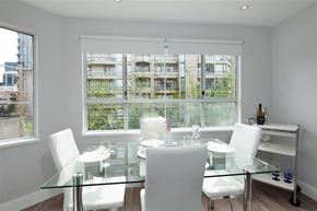 Vancouver apartment for rent - A glass dining table with four chairs in front of a window with a view of a building.