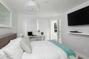 Vancouver apartment for rent - A bedroom with a bed, a desk with a laptop, and a television on the wall.