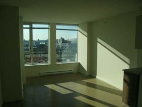 Vancouver apartment for rent - A room with a large window overlooking a cityscape.