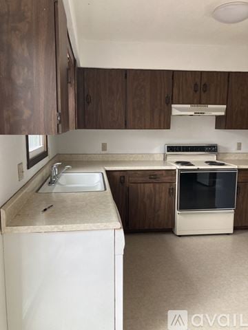 Des Moines house for rent - A kitchen with a white dishwasher and brown cabinets.