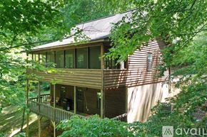 Blairsville house for rent - A wooden house with a balcony is surrounded by green trees.