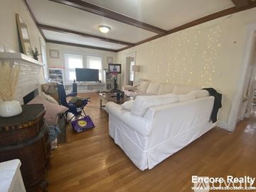 Boston house for rent - A living room with a white couch and wooden floors.