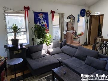 Brighton house for rent - A living room with a grey couch and a wooden coffee table.