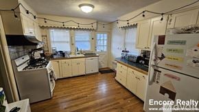Boston house for rent - A kitchen with wooden floors and white cabinets.
