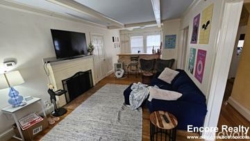 Boston house for rent - A living room with a fireplace and a television on the wall.