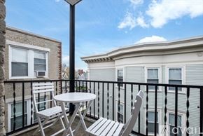 Boston apartment for rent - A balcony with a table and chairs overlooks a building.