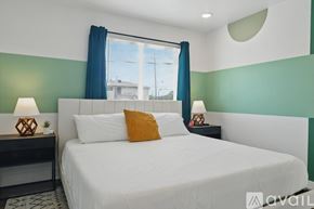 Dallas apartment for rent - A bedroom with a white bed and a window with blue curtains.