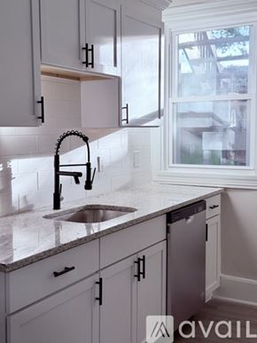 Stamford house for rent - A kitchen with white cabinets and a black faucet.