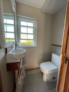 Greensburg house for rent - A small bathroom with a toilet, sink, and window.