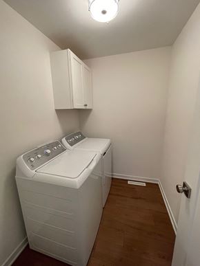 Belgium apartment for rent - A small white washing machine sits in a small room.