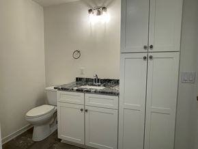 Belgium apartment for rent - A white bathroom with a toilet, sink, and cabinets.