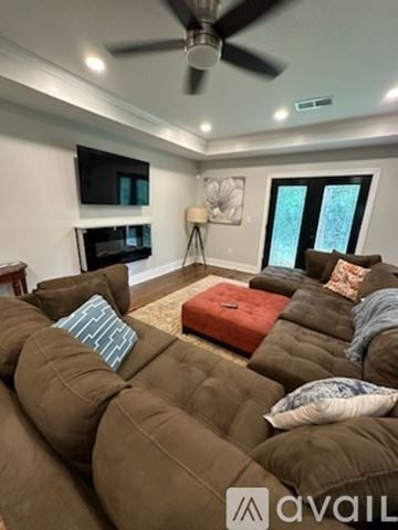 Atlanta house for rent - A living room with a brown couch and a ceiling fan.