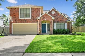 Friendswood house for rent - A red brick house with a garage door and a green lawn.