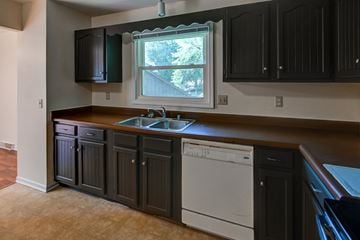 Madison house for rent - A kitchen with dark brown cabinets and a white dishwasher.