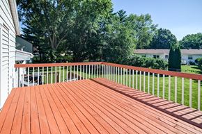 Madison house for rent - A wooden deck with a white railing and trees in the background.