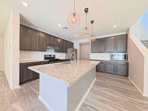 Chino house for rent - A kitchen with a marble island and dark brown cabinets.