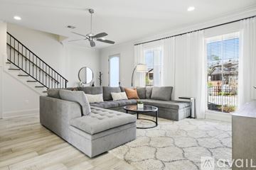 Baton Rouge house for rent - A living room with a grey couch and a round mirror on the wall.