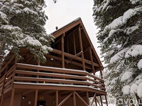 Truckee house for rent - A wooden cabin in the woods covered in snow.