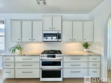 Buckeye house for rent - A kitchen with white cabinets and a black stove top oven.