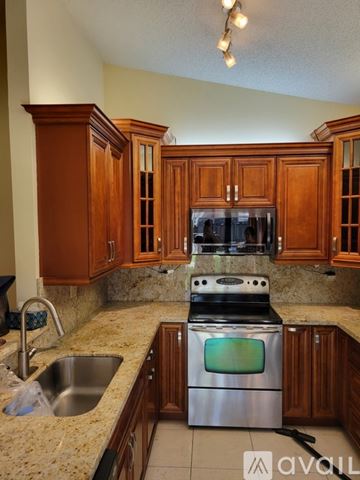 Davie house for rent - A kitchen with wooden cabinets and granite countertops.