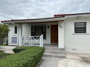 Miami house for rent - A white house with a brown door and a sign that says "available".