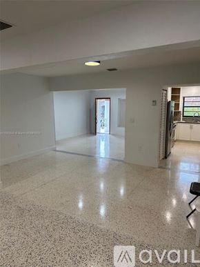 Miami house for rent - A spacious room with a marble floor and a doorway leading to another room.