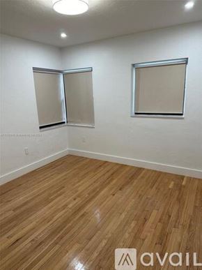 Miami house for rent - A room with wooden flooring and two windows.