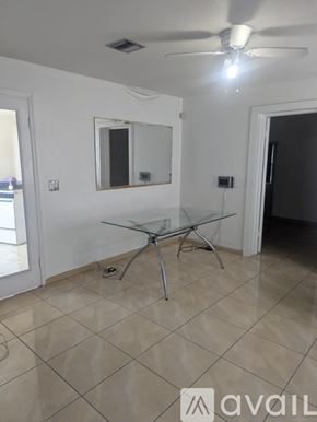 Miami house for rent - A room with a glass table and a ceiling fan.
