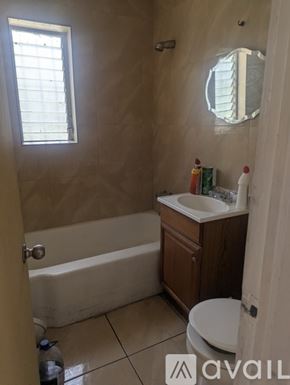Miami house for rent - A bathroom with a tub, toilet, sink and mirror.