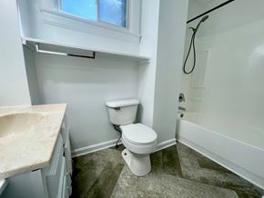 Louisville apartment for rent - A white toilet sits in a bathroom next to a sink and a bathtub.