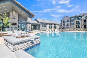 Erie apartment for rent - A large swimming pool with a stone bench in front of a modern building.