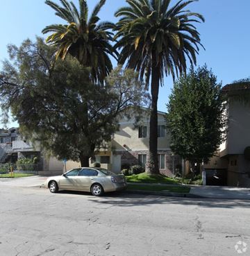 Burbank apartment for rent - A car is parked on the side of a street with palm trees in the background.