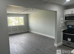 Keansburg apartment for rent - A spacious empty room with a window and a microwave.