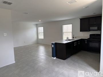 Fort Worth house for rent - A kitchen with black cabinets and a blue trash can.